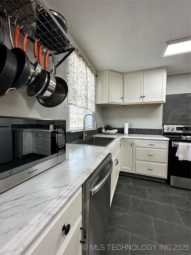 8815 Ashcroft Rd, Mounds, OK 74047 - kitchen with dark tile patterned floors, a sink, white cabinetry, a textured ceiling, and appliances with stainless steel finishes