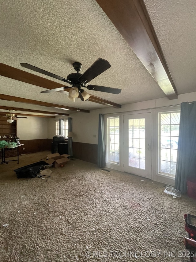 living room with carpet, a wainscoted wall, a healthy amount of sunlight, and a textured ceiling