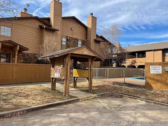 exterior space featuring stone siding, a chimney, and fence