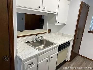 kitchen with light countertops, white cabinets, a sink, and dishwasher
