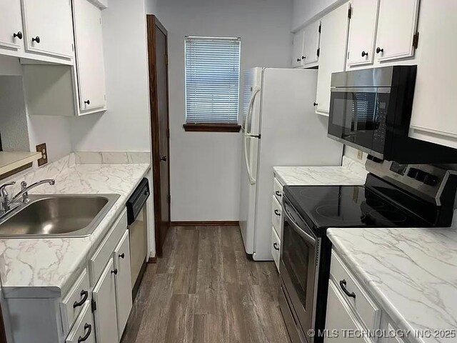 kitchen with a sink, white cabinetry, dark wood-type flooring, baseboards, and appliances with stainless steel finishes