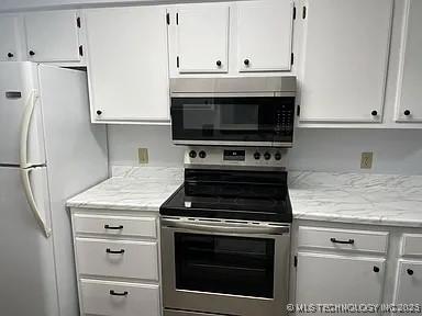 kitchen with light stone counters, white cabinets, and appliances with stainless steel finishes