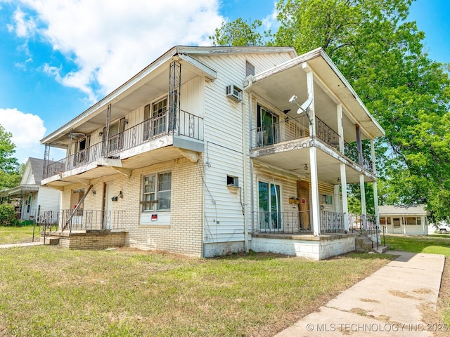 view of front of property with covered porch, an AC wall unit, a front lawn, and a balcony