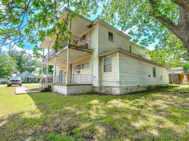 view of property exterior with a balcony, a lawn, fence, covered porch, and crawl space