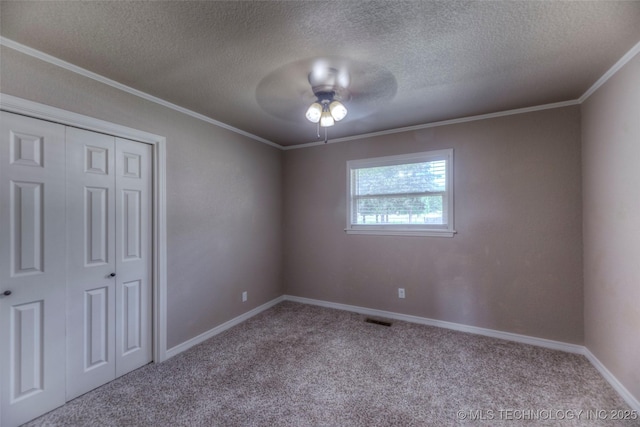 unfurnished bedroom with crown molding, a textured ceiling, visible vents, and carpet