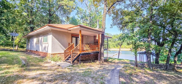 view of front of property featuring a porch, a water view, stucco siding, and stairway