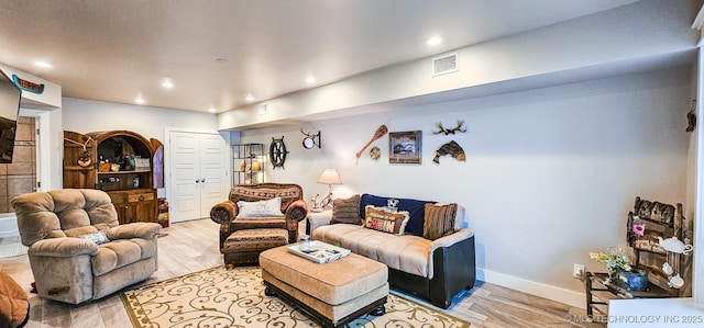living area featuring light wood-type flooring, visible vents, arched walkways, and recessed lighting