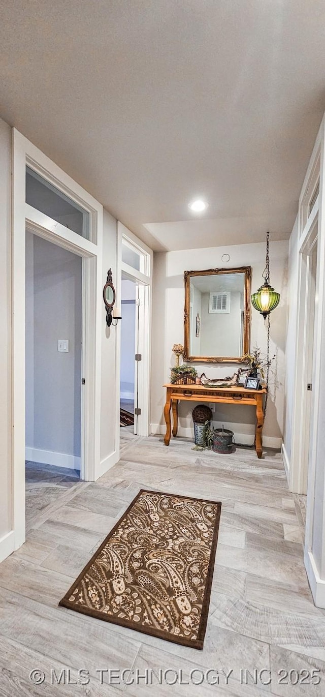 corridor with visible vents, wood finished floors, and baseboards