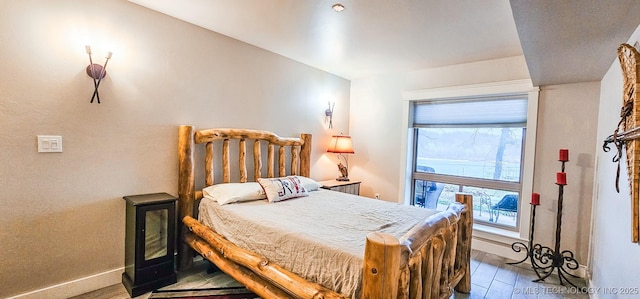 bedroom featuring wood finished floors, baseboards, and multiple windows
