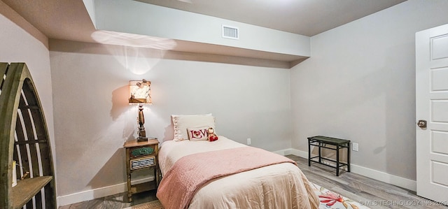 bedroom featuring baseboards, visible vents, and wood finished floors
