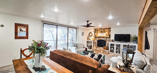 living area featuring a fireplace, ceiling fan, recessed lighting, and wood finished floors