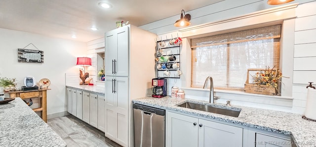 kitchen with a sink, stainless steel dishwasher, light stone counters, and recessed lighting