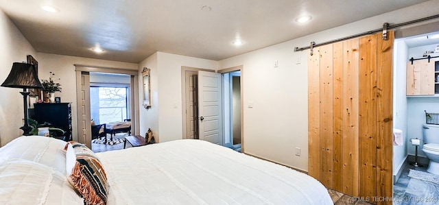 bedroom with access to outside, wood finished floors, a barn door, and recessed lighting