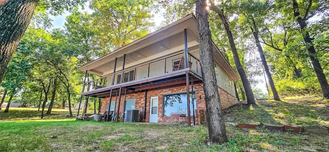rear view of property with a balcony, central air condition unit, and brick siding