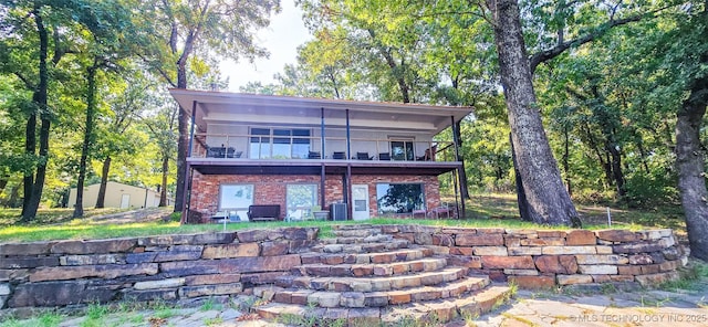 back of property with a balcony and brick siding