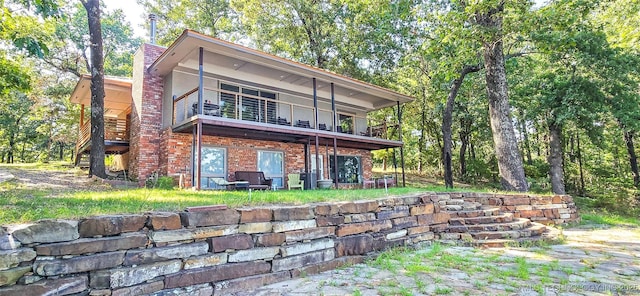 rear view of house with brick siding and a balcony