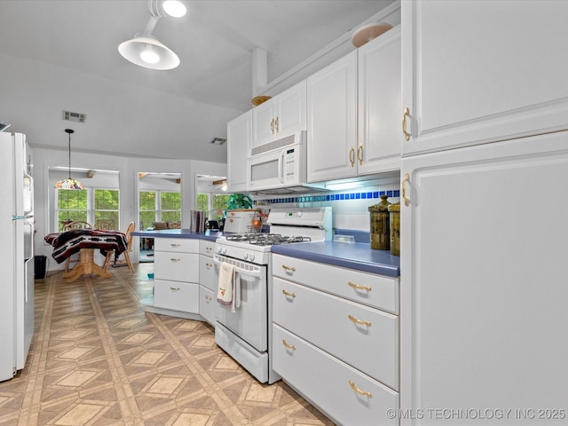 kitchen with white cabinets, dark countertops, visible vents, and white appliances