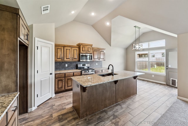 5113 S Walnut Creek Dr, Sand Springs, OK 74063 - kitchen with stainless steel appliances, a sink, lofted ceiling, a breakfast bar, and light stone counters