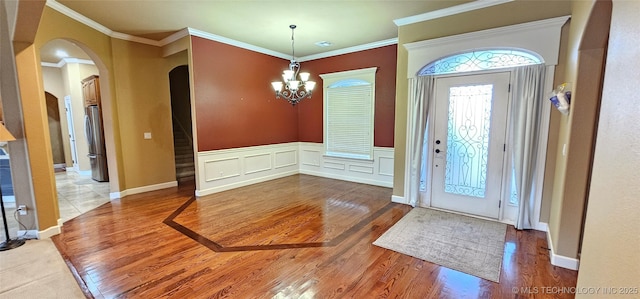 2501 Forest Ridge Parkway, Claremore, OK 74017 - entrance foyer with arched walkways, wood finished floors, a chandelier, ornamental molding, and wainscoting