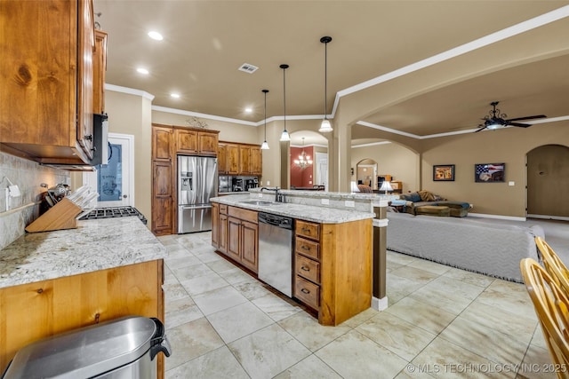2501 Forest Ridge Parkway, Claremore, OK 74017 - kitchen featuring appliances with stainless steel finishes, arched walkways, a sink, brown cabinets, and crown molding