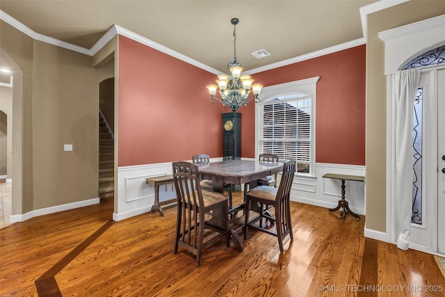 2501 Forest Ridge Parkway, Claremore, OK 74017 - dining area featuring arched walkways, wood finished floors, a chandelier, stairway, and crown molding