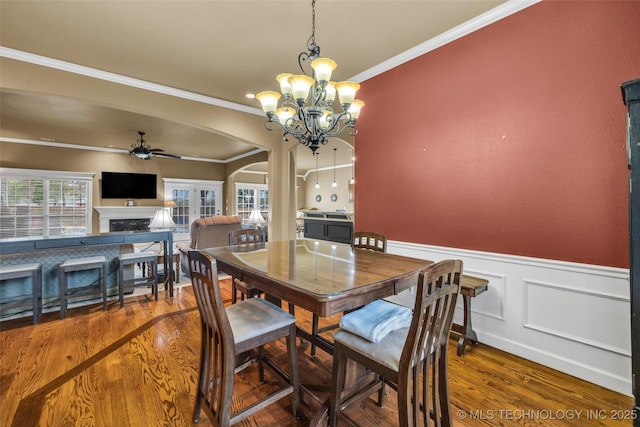 2501 Forest Ridge Parkway, Claremore, OK 74017 - dining room featuring arched walkways, ceiling fan, a fireplace, ornamental molding, and wood finished floors
