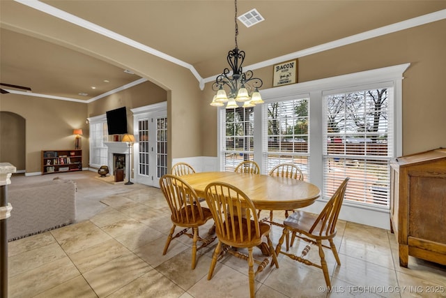 2501 Forest Ridge Parkway, Claremore, OK 74017 - dining area with crown molding, healthy amount of natural light, arched walkways, a chandelier, and a wainscoted wall