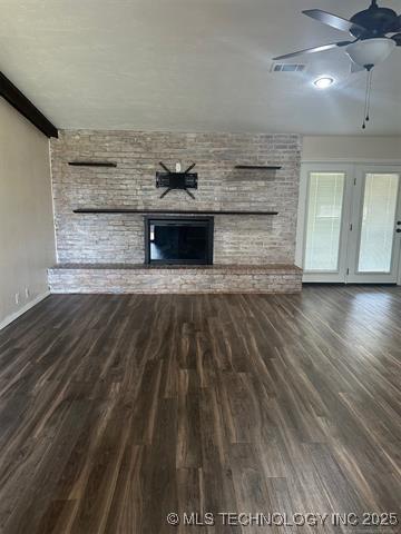 1607 Kay, Durant, OK 74701 - unfurnished living room with visible vents, wood finished floors, a ceiling fan, and a brick fireplace
