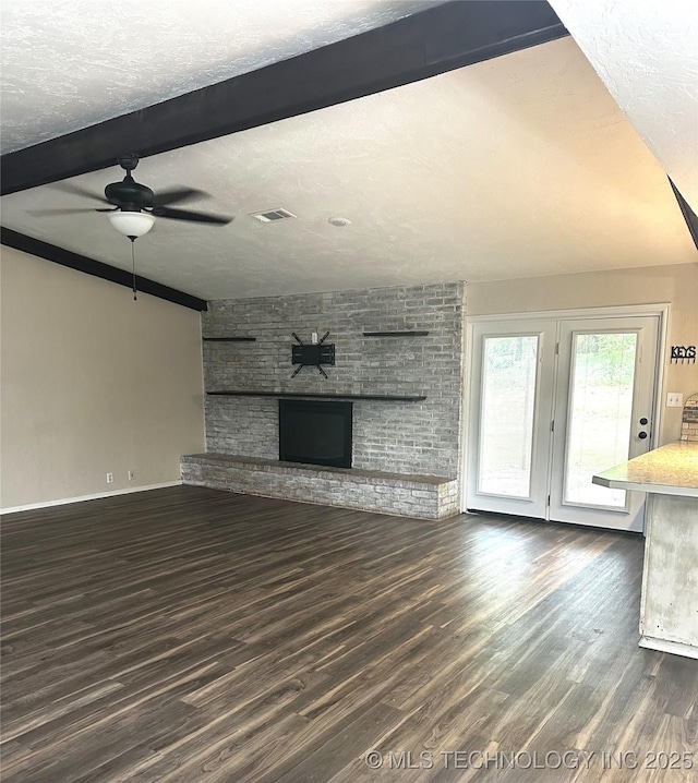 1607 Kay, Durant, OK 74701 - unfurnished living room featuring beam ceiling, dark wood-style floors, a ceiling fan, a brick fireplace, and baseboards