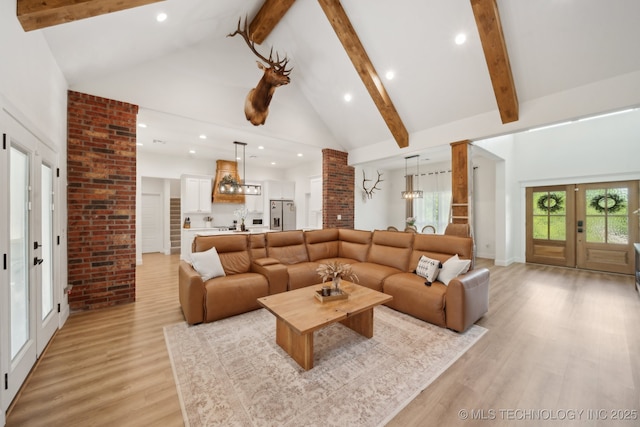 living area with french doors, beam ceiling, high vaulted ceiling, recessed lighting, and light wood-style flooring