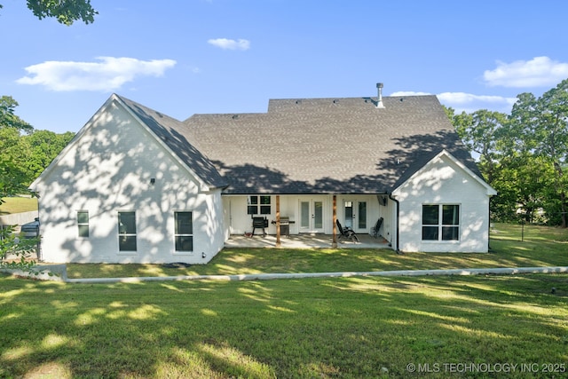 rear view of house featuring a lawn, french doors, brick siding, a patio, and a shingled roof