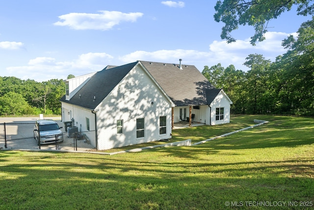 back of property with a gate, fence, and a lawn