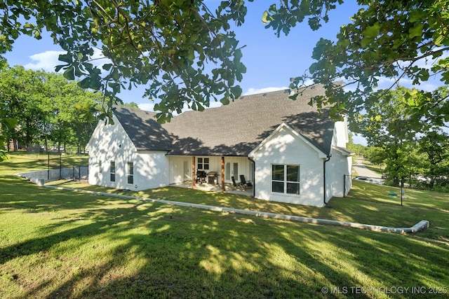 rear view of house with a yard, a patio, and roof with shingles