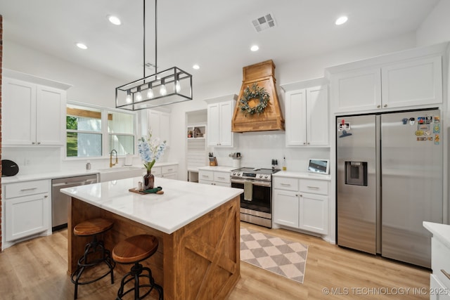 kitchen featuring custom exhaust hood, visible vents, white cabinetry, a kitchen island, and stainless steel appliances
