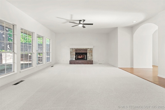 9624 S 68th E Ave, Tulsa, OK 74133 - unfurnished living room with visible vents, a fireplace, carpet floors, a ceiling fan, and arched walkways