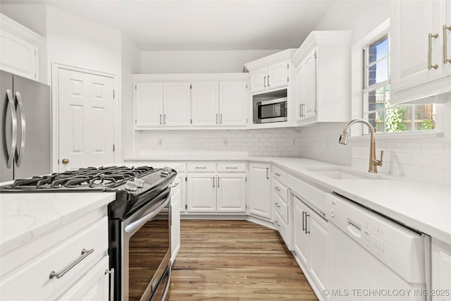 9624 S 68th E Ave, Tulsa, OK 74133 - kitchen featuring a sink, white cabinetry, decorative backsplash, light wood-style floors, and appliances with stainless steel finishes