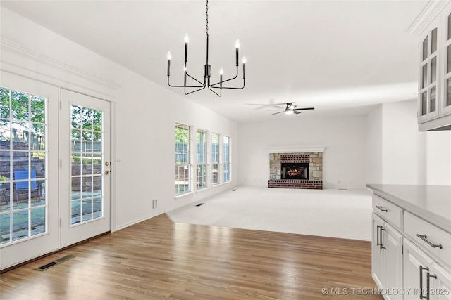 9624 S 68th E Ave, Tulsa, OK 74133 - unfurnished living room featuring a fireplace, light wood finished floors, ceiling fan with notable chandelier, and visible vents