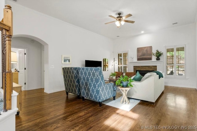 6811 S Sycamore Pl, Broken Arrow, OK 74011 - living room with wood finished floors, a ceiling fan, arched walkways, a fireplace, and baseboards