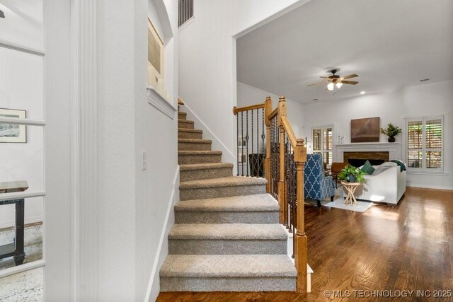6811 S Sycamore Pl, Broken Arrow, OK 74011 - stairs with a ceiling fan, wood finished floors, and a fireplace
