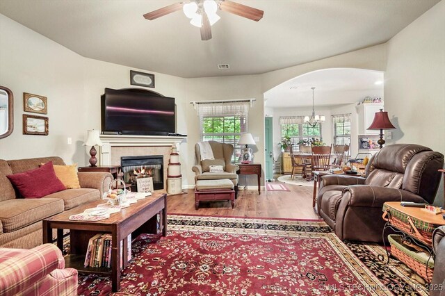 living room with arched walkways, a ceiling fan, plenty of natural light, and wood finished floors