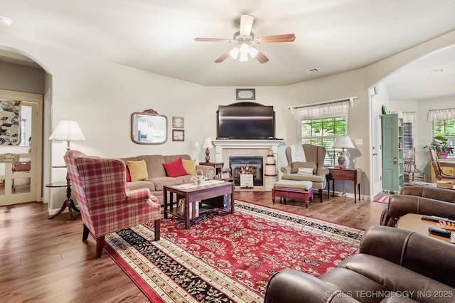living room featuring arched walkways, plenty of natural light, and wood finished floors