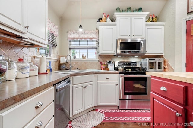 kitchen featuring appliances with stainless steel finishes, a sink, tasteful backsplash, and white cabinetry