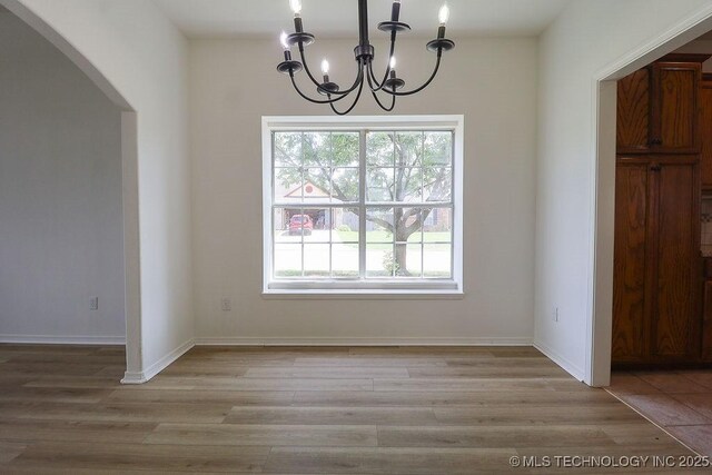 3934 S 199th E Ave, Broken Arrow, OK 74014 - unfurnished dining area with arched walkways, a chandelier, and light wood finished floors