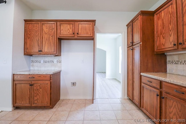 3934 S 199th E Ave, Broken Arrow, OK 74014 - kitchen with brown cabinets, tasteful backsplash, light tile patterned floors, and light stone countertops