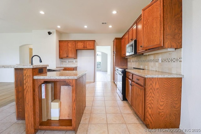 3934 S 199th E Ave, Broken Arrow, OK 74014 - kitchen with electric stove, stainless steel microwave, arched walkways, brown cabinetry, and tasteful backsplash