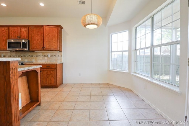 3934 S 199th E Ave, Broken Arrow, OK 74014 - kitchen featuring stainless steel microwave, brown cabinets, light countertops, decorative backsplash, and recessed lighting