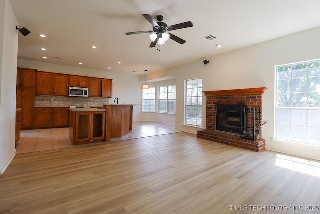 3934 S 199th E Ave, Broken Arrow, OK 74014 - kitchen featuring stainless steel microwave, open floor plan, brown cabinetry, recessed lighting, and light wood-style floors
