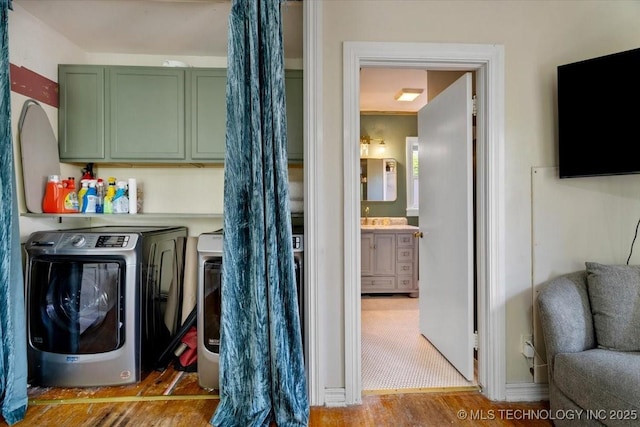 laundry area featuring washer and dryer, cabinet space, and wood finished floors