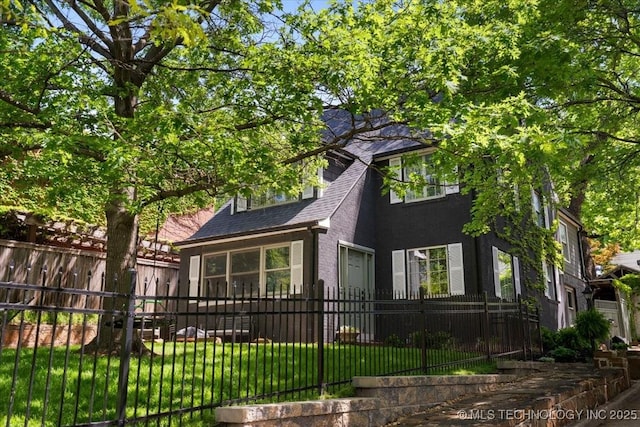 exterior space featuring a front lawn, a shingled roof, stucco siding, and fence private yard