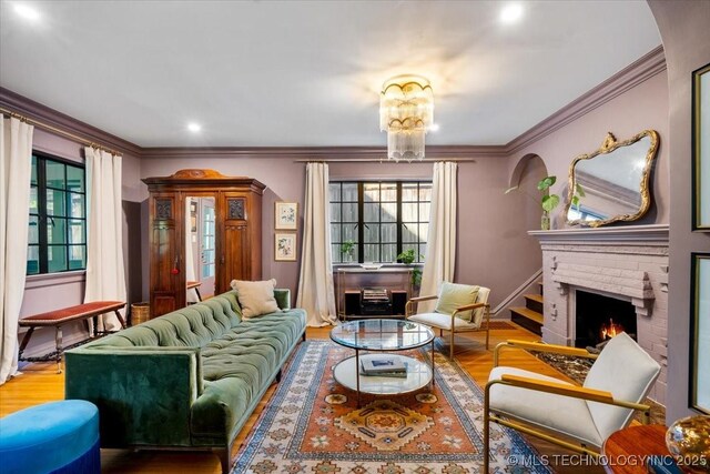 living room featuring a wealth of natural light, a fireplace, crown molding, and wood finished floors